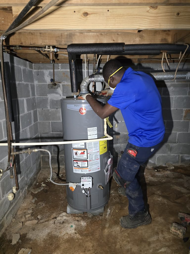 A plumber works on a water heater.
